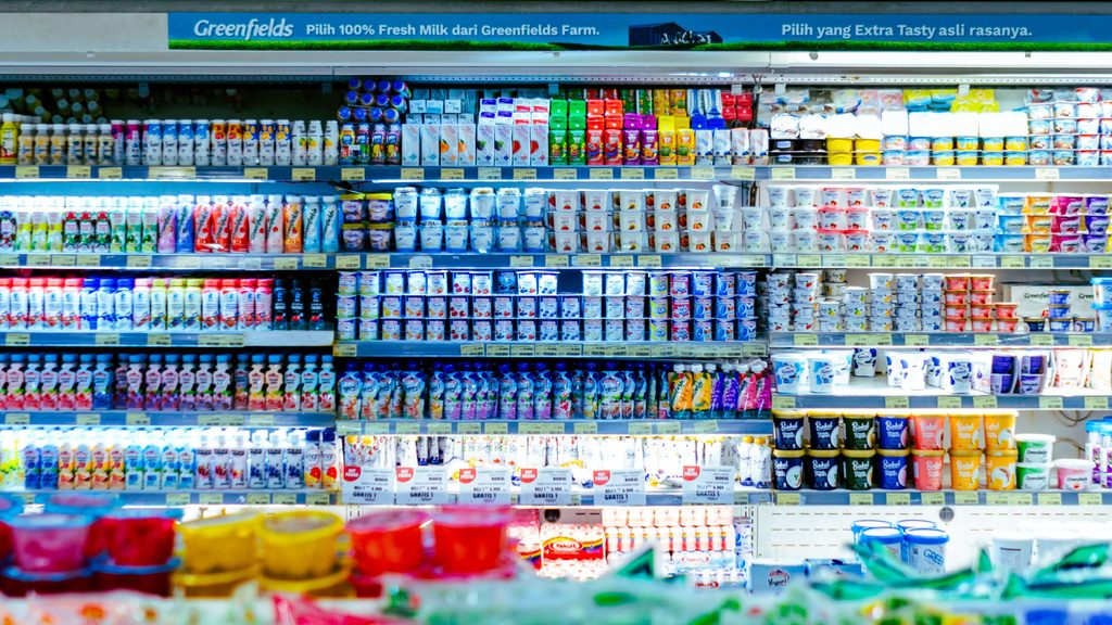 Полиці супермаркету з рядами яскравих йогуртів і молочних продуктів – приклад товарів, у складі яких є Е-добавки